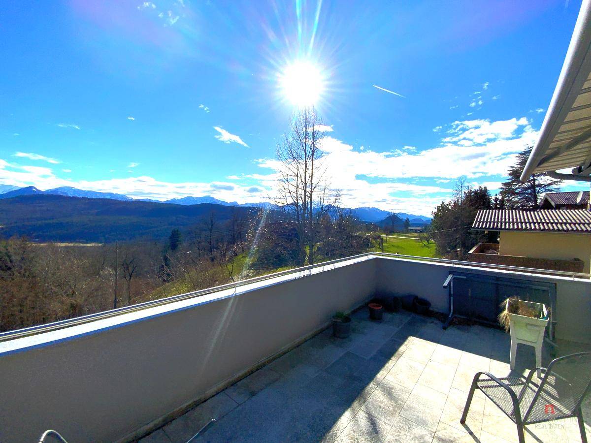 Sonniger Terrassenbereich mit weitem Blick auf die umliegende Landschaft und Berge.