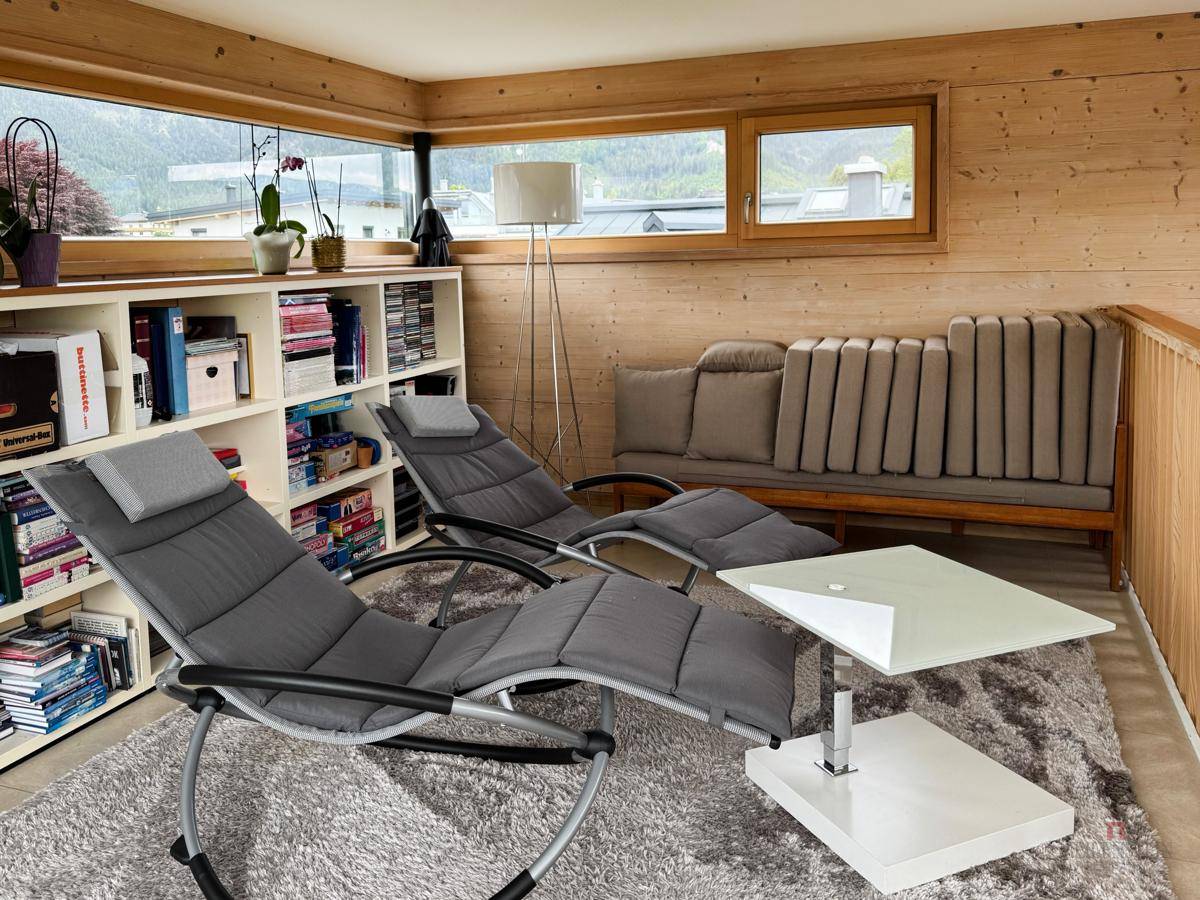 Entspannungsbereich mit Liegestühlen, Bücherregal und Holzwänden, ideal zum Verweilen.