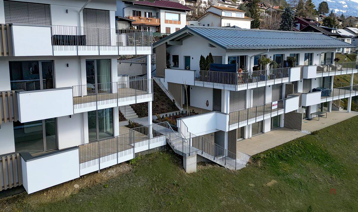 Ansicht der modernen Wohnanlage mit mehreren Balkonen, Terrassen und Zugangswegen.