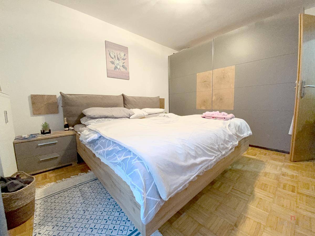 Schlafzimmer mit komfortablem Holzbett, weißer Bettwäsche und großem Einbauschrank.