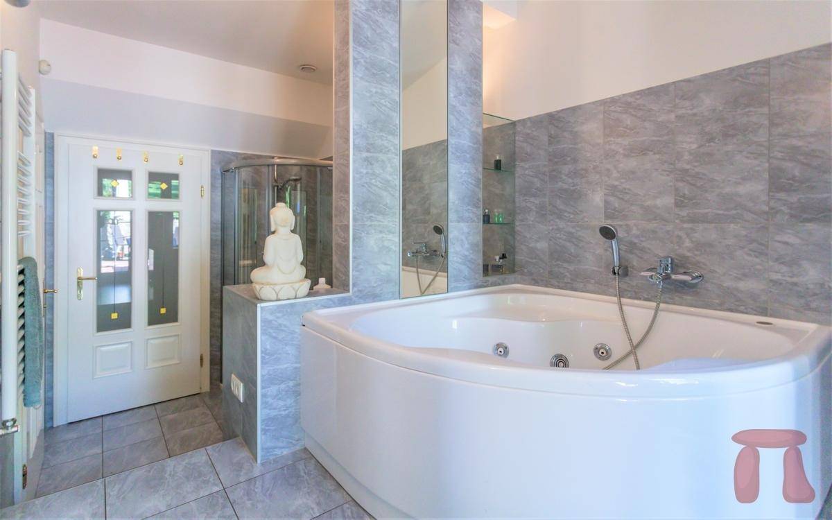 Geräumiges Badezimmer mit Eckbadewanne, separater Dusche und grauen Fliesen.