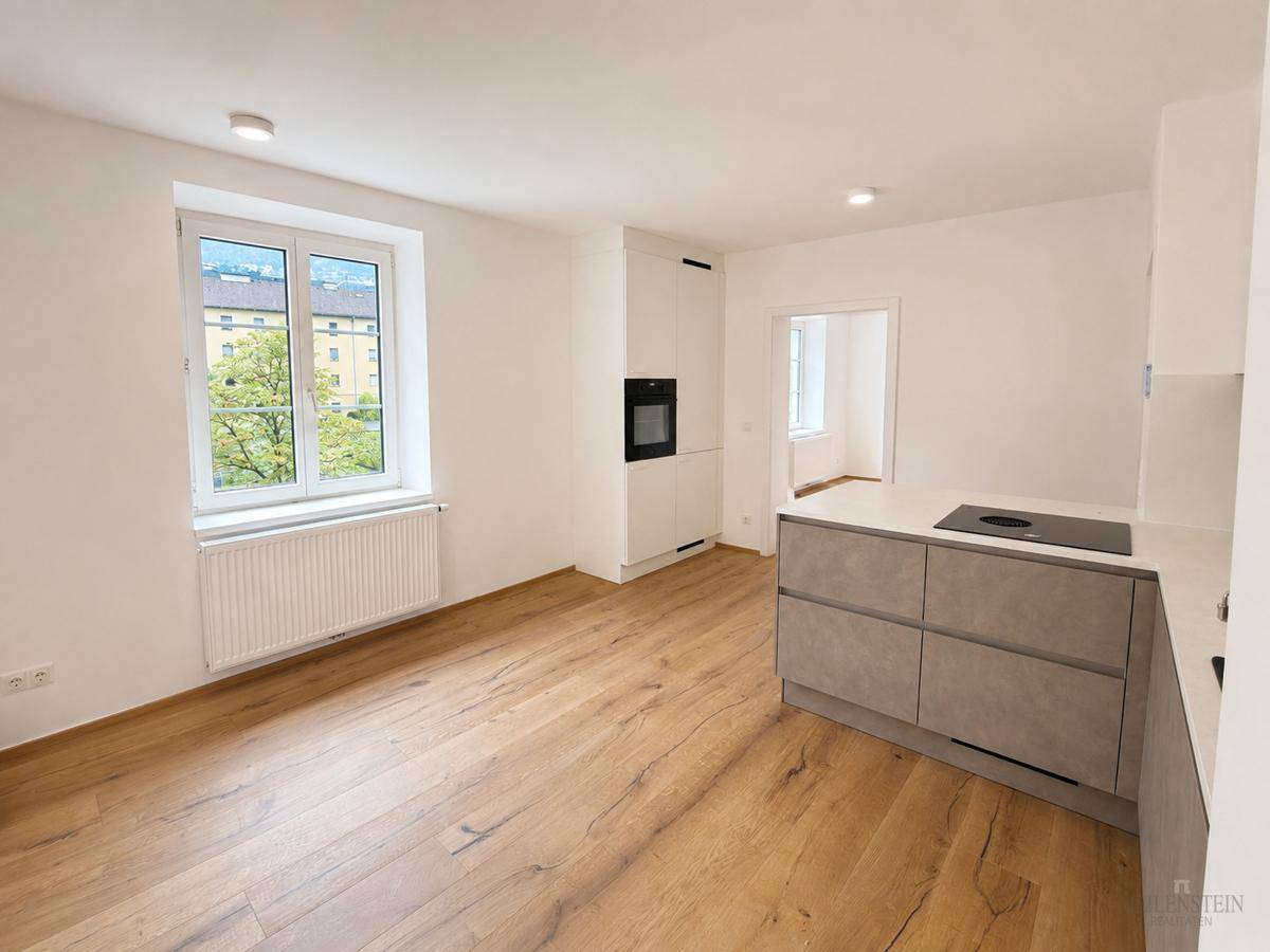 Heller Küchenbereich mit Fenster und Blick ins Freie, offen gestaltet mit Holzboden.