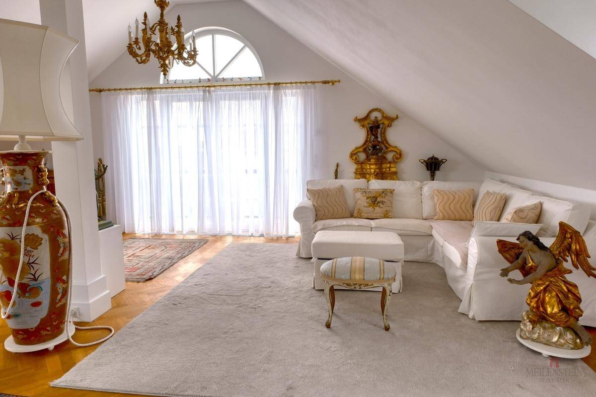 Helles Wohnzimmer im Dachgeschoss mit Dachschrägen, Teppich und eleganten Möbeln.