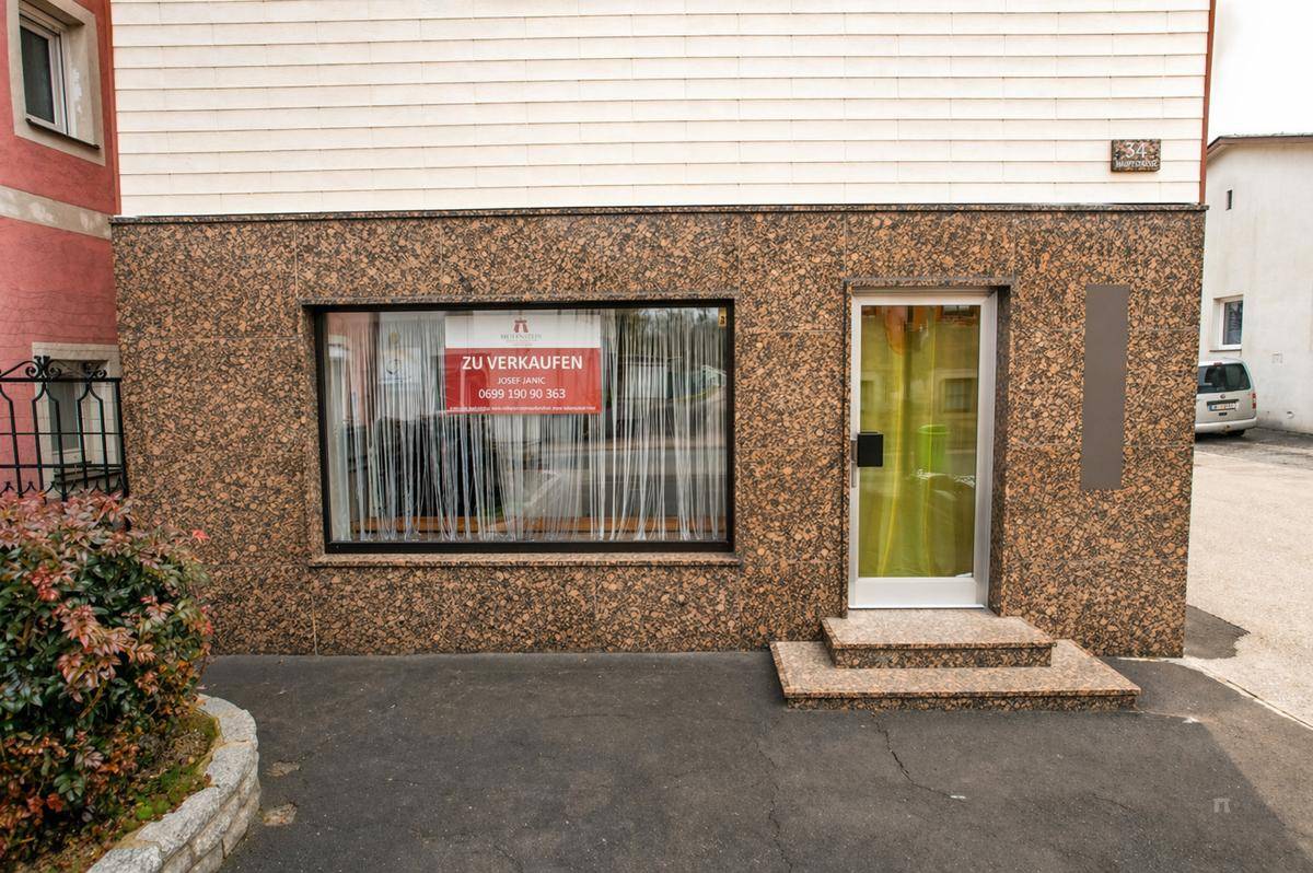 Erdgeschossfassade des Hauses mit einem Schaufenster und Eingangstür, verziert mit braunem Granit.