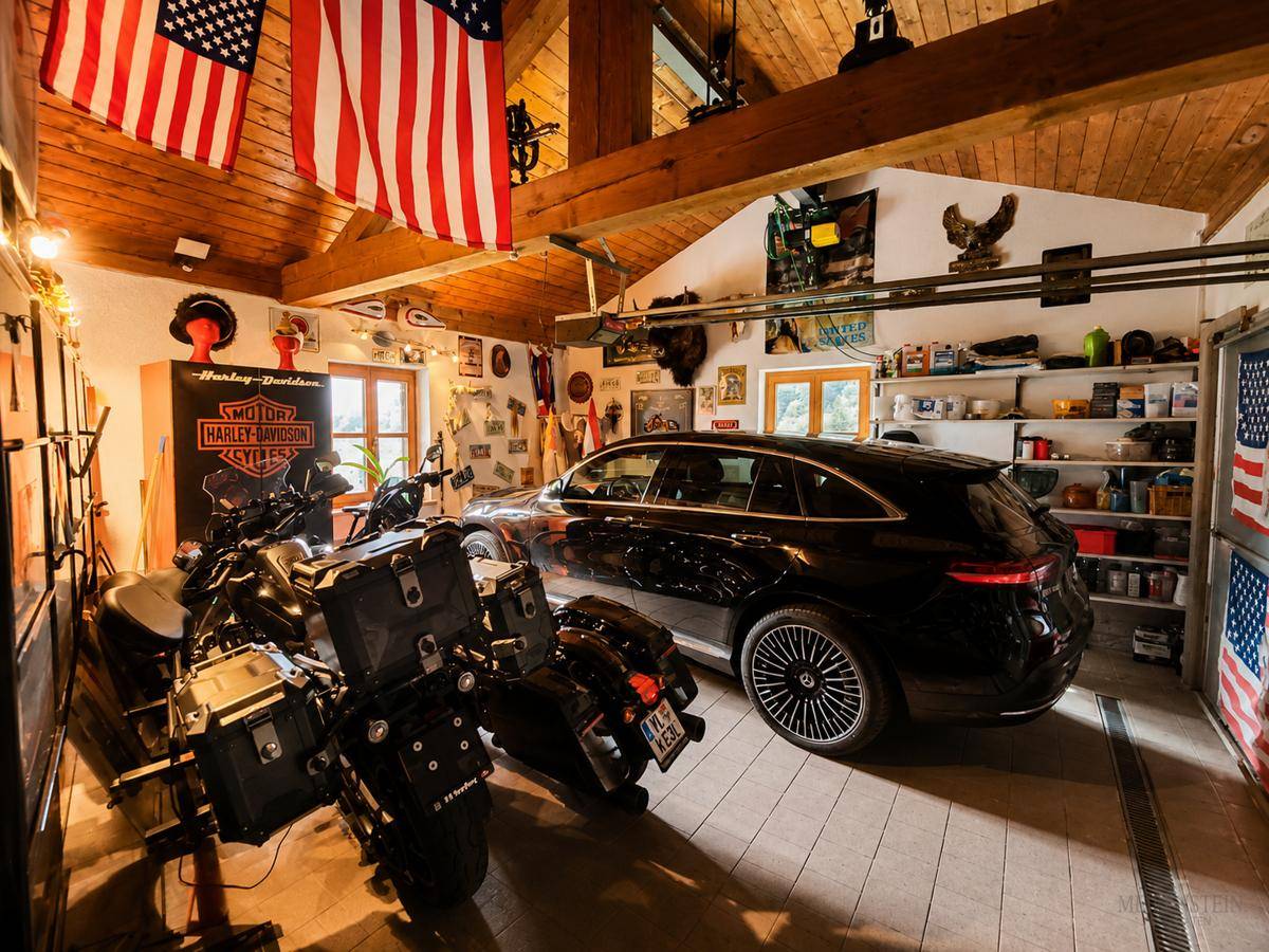 Geräumige Garage mit Holzbalkendecke, Platz für Fahrzeuge und Motorräder sowie dekorativen Elementen.