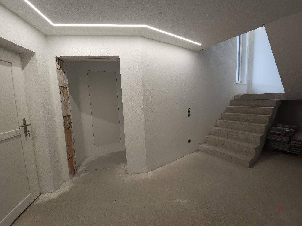 Unfertiger Flurbereich mit Treppe und moderner Deckenbeleuchtung.
