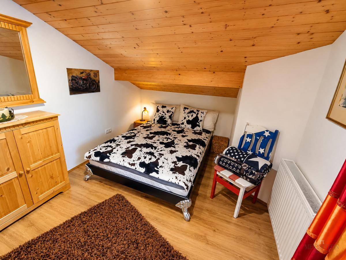 Gemütliches Schlafzimmer im Dachgeschoss mit Holzdecke, Holzboden und einem Doppelbett.
