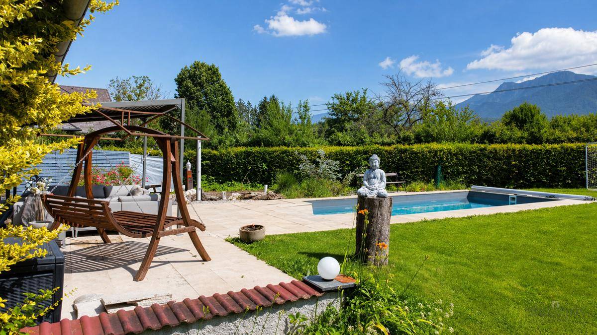 Sonniger Garten mit Pool, Schaukel und Blick auf die umliegende Berglandschaft.