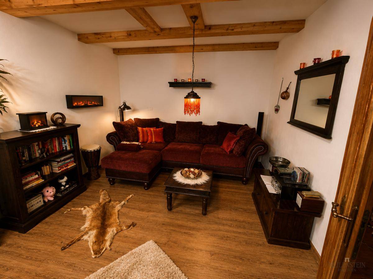 Gemütliches Wohnzimmer mit Holzbalken, rotem Sofa und dekorativen Elementen im Landhausstil.