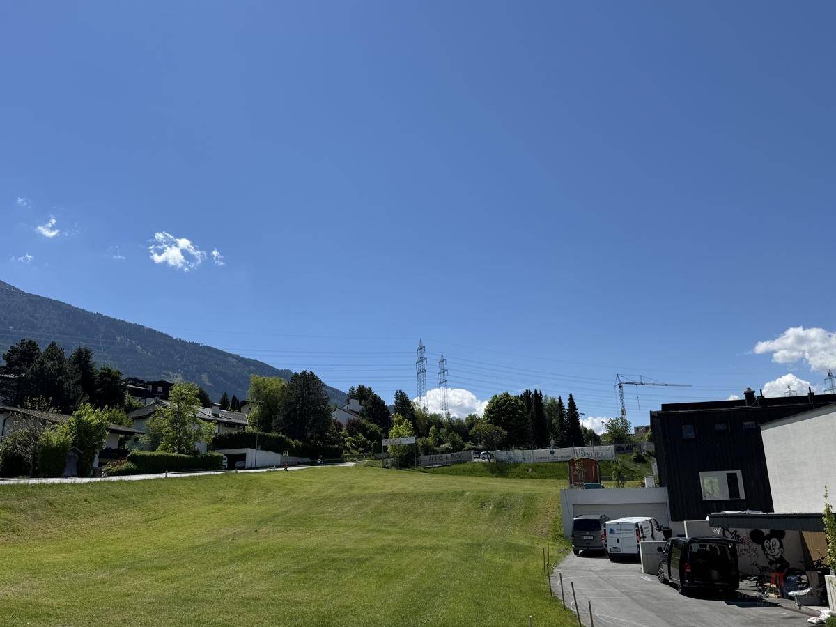 Weitläufige Grünfläche mit Blick auf die umliegende Wohnbebauung und Strommasten.