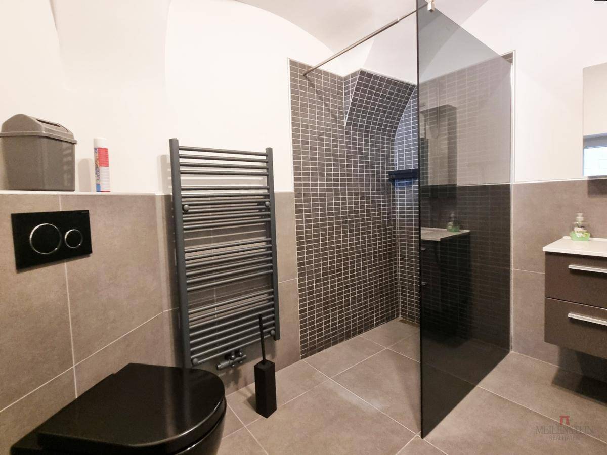 Stilvolles Badezimmer mit dunkler Duschkabine, hängendem WC und modernem Waschtisch.