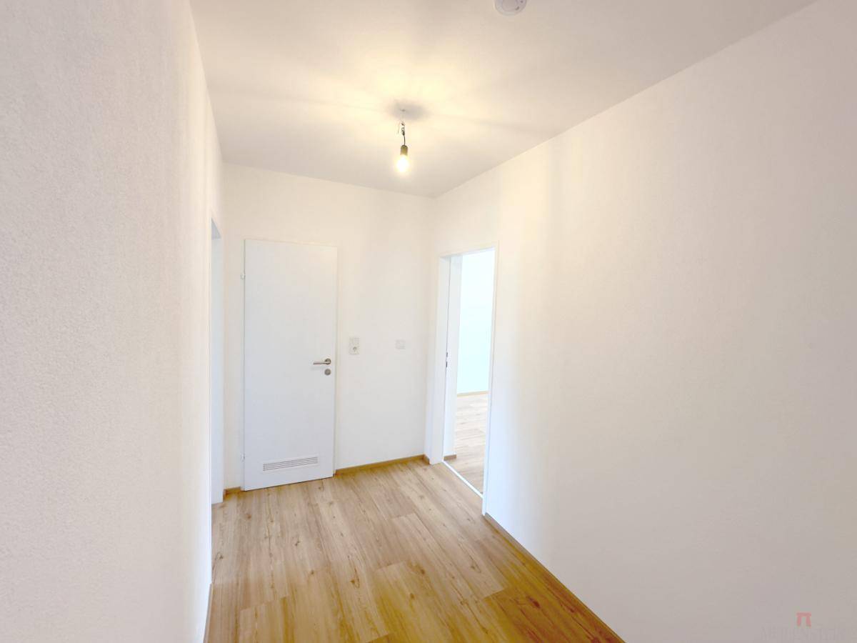 Heller Flur mit Holzfußboden und weißen Türen, der zu weiteren Räumen führt.