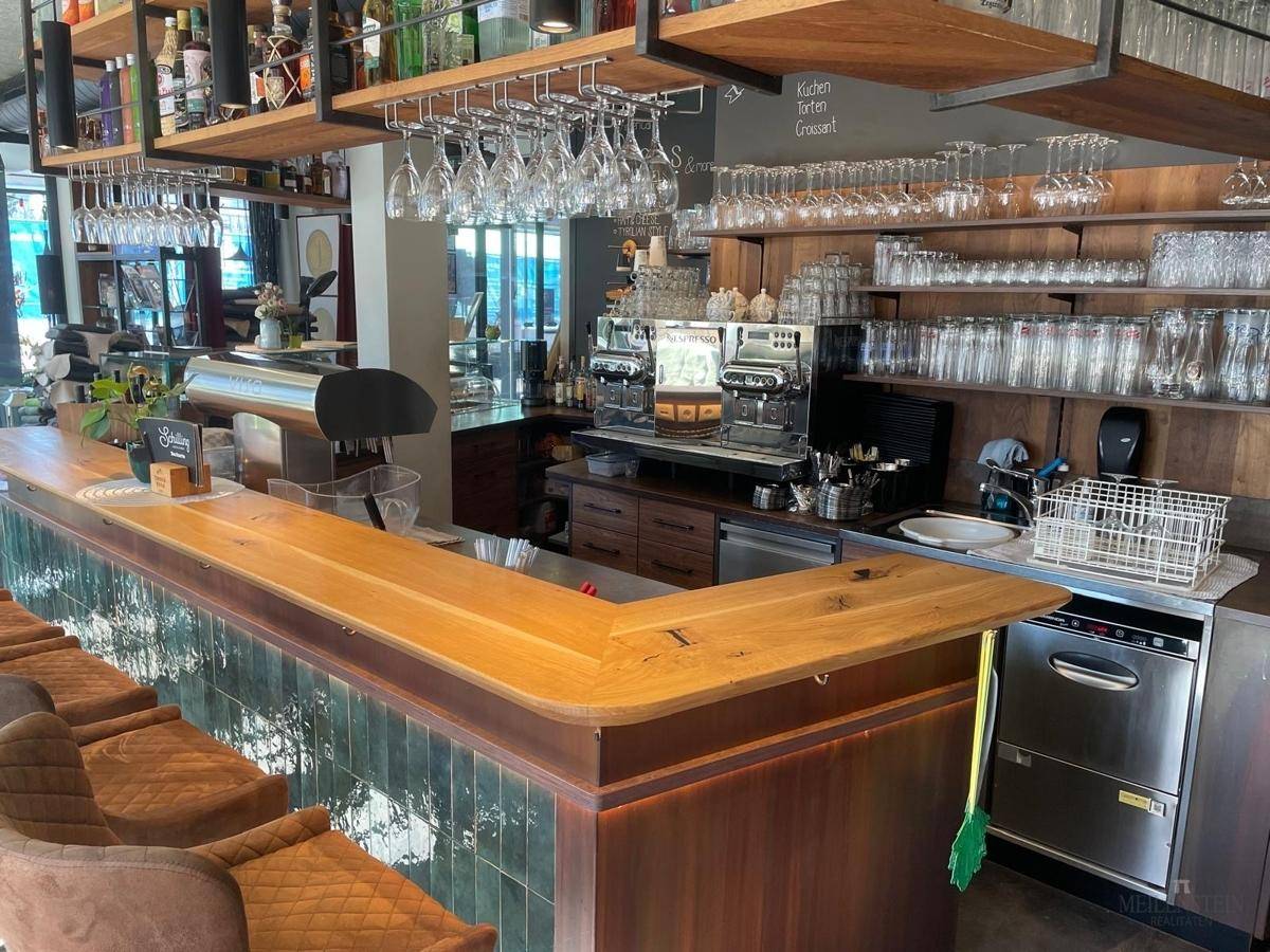 Professionelle Bar mit Kaffeemaschinen, Spülbecken und integriertem Geschirrspüler hinter der Theke.