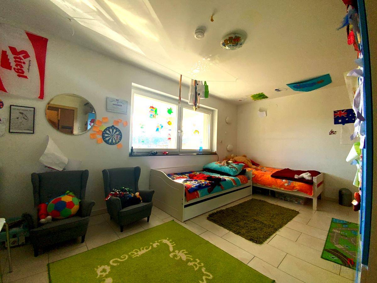 Helles Kinderzimmer mit zwei Betten, Spielzeug und bunten Dekorationen an den Wänden.
