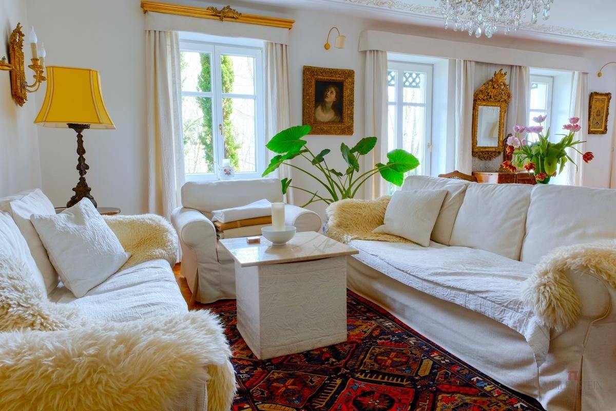 Helles Wohnzimmer mit bequemen weißen Sofas, Teppichen und Blick ins Grüne.