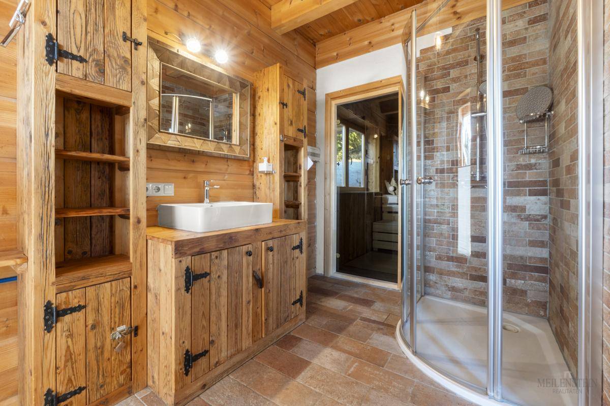 Rustikales Badezimmer mit Holzmöbeln, Aufsatzwaschbecken und gemauerter Dusche.