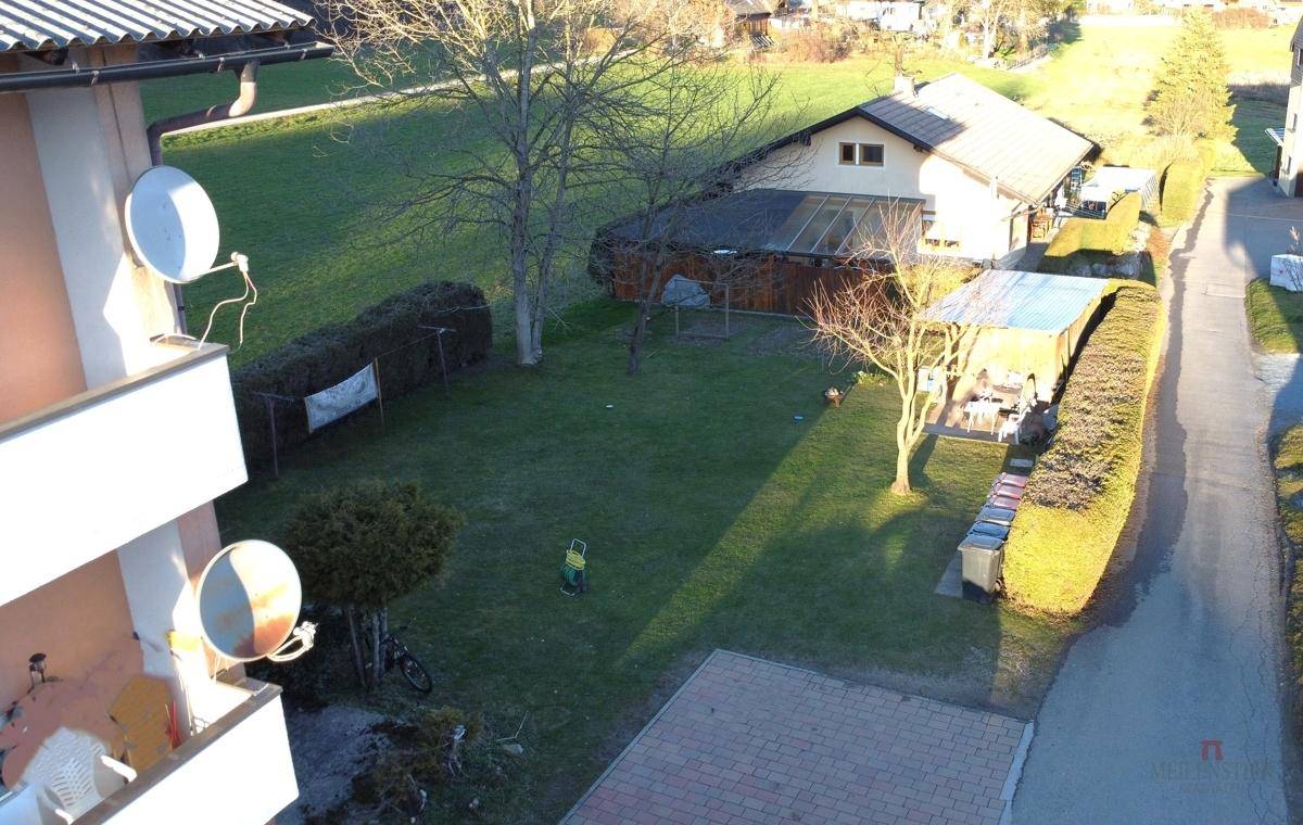 Gepflegter Gartenbereich mit Rasenfläche, Hecken und Bäumen hinter dem Wohngebäude.