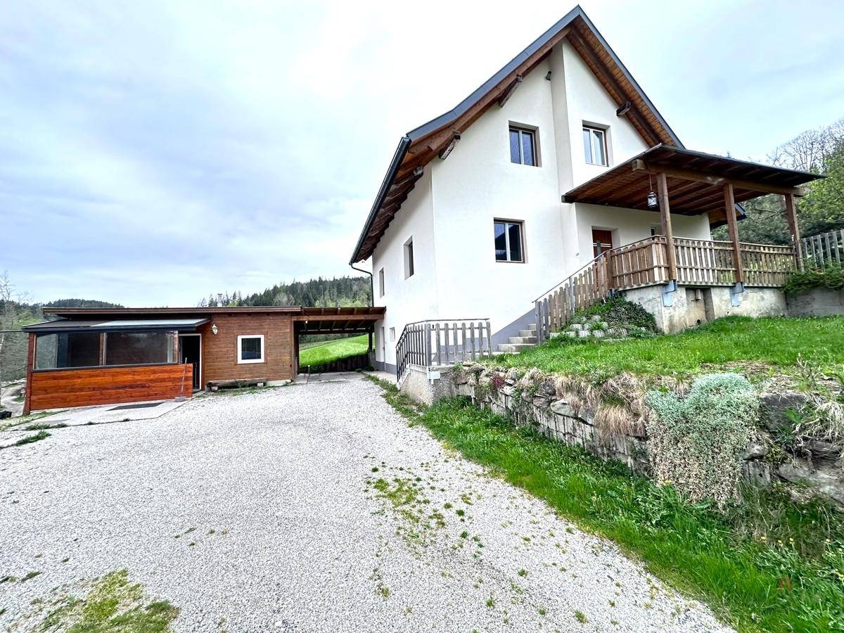 Ansicht des Hauses von der Einfahrt aus mit Kiesweg und einem überdachten Eingangsbereich.