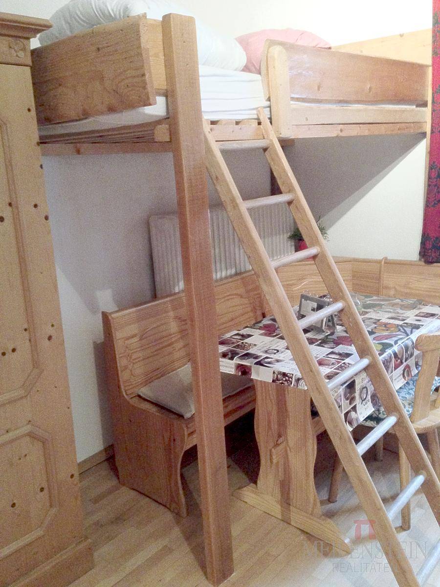 Gemütliches Zimmer mit Hochbett, Holztisch und Sitzbank im rustikalen Stil.