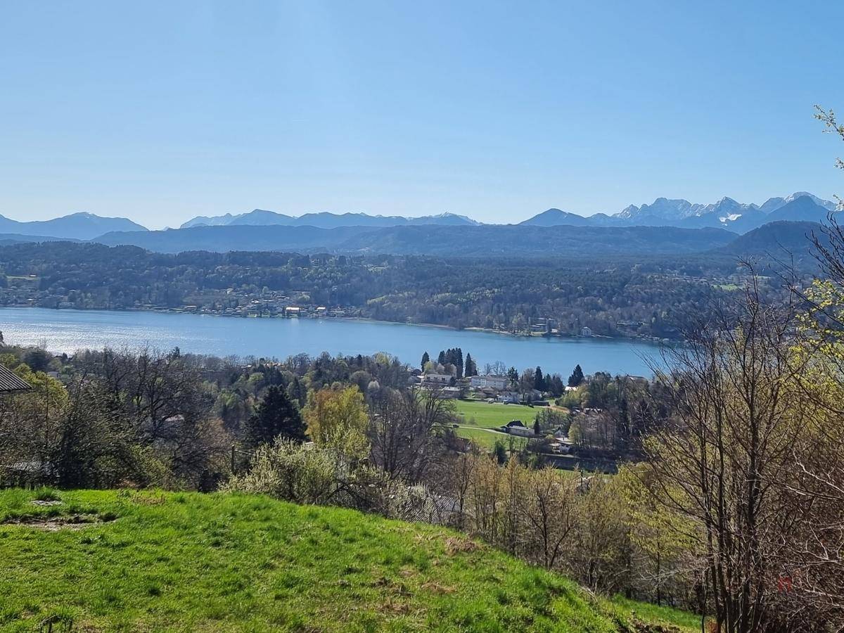 Panoramablick auf einen See und die umliegende Berglandschaft unter klarem blauem Himmel.