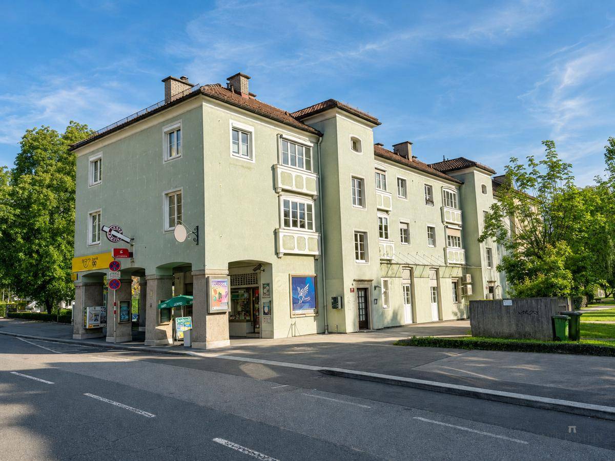 Historisches Gebäude mit Geschäften im Erdgeschoss und klassischer Architektur an einer Straße gelegen.