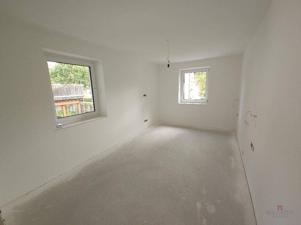Helles Schlafzimmer im Rohbau mit zwei Fenstern, bereit für den Innenausbau.