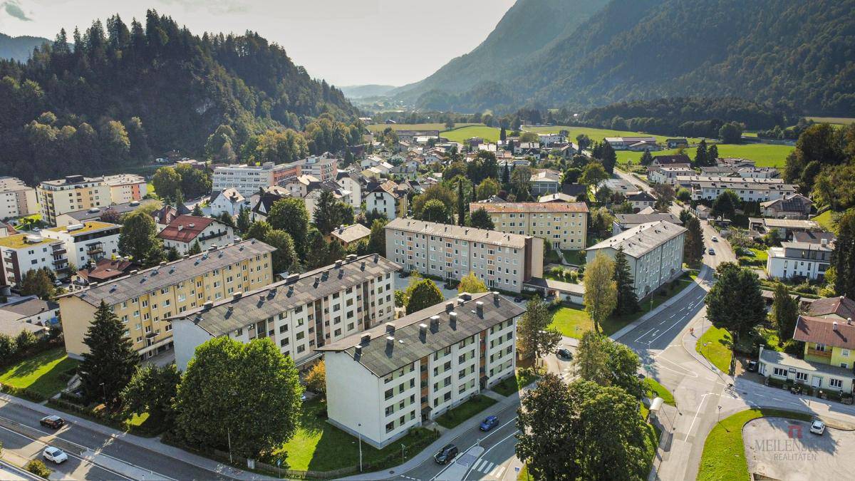 Weitläufige Luftaufnahme einer Wohnsiedlung eingebettet in eine grüne Berglandschaft.