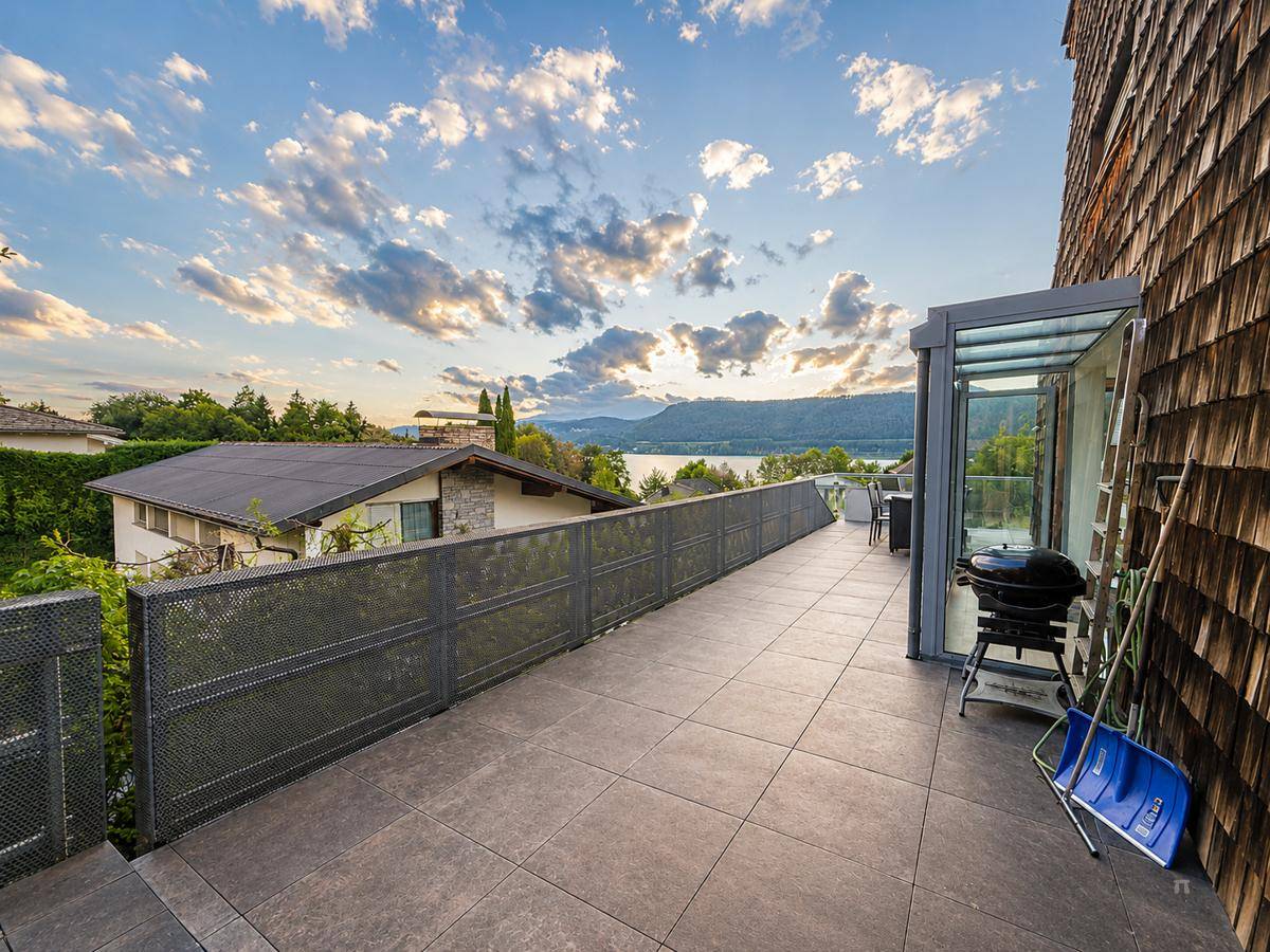 Lange, geflieste Terrasse mit Grill und Seeblick, ideal für Outdoor-Aktivitäten und Entspannung.