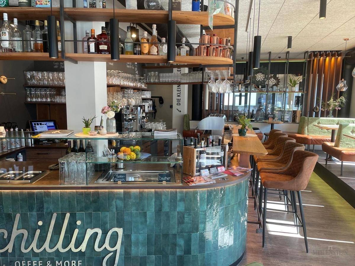 Detailansicht der modernen Bar mit grünen Fliesen, Kaffeemaschine und Auslage für Speisen.