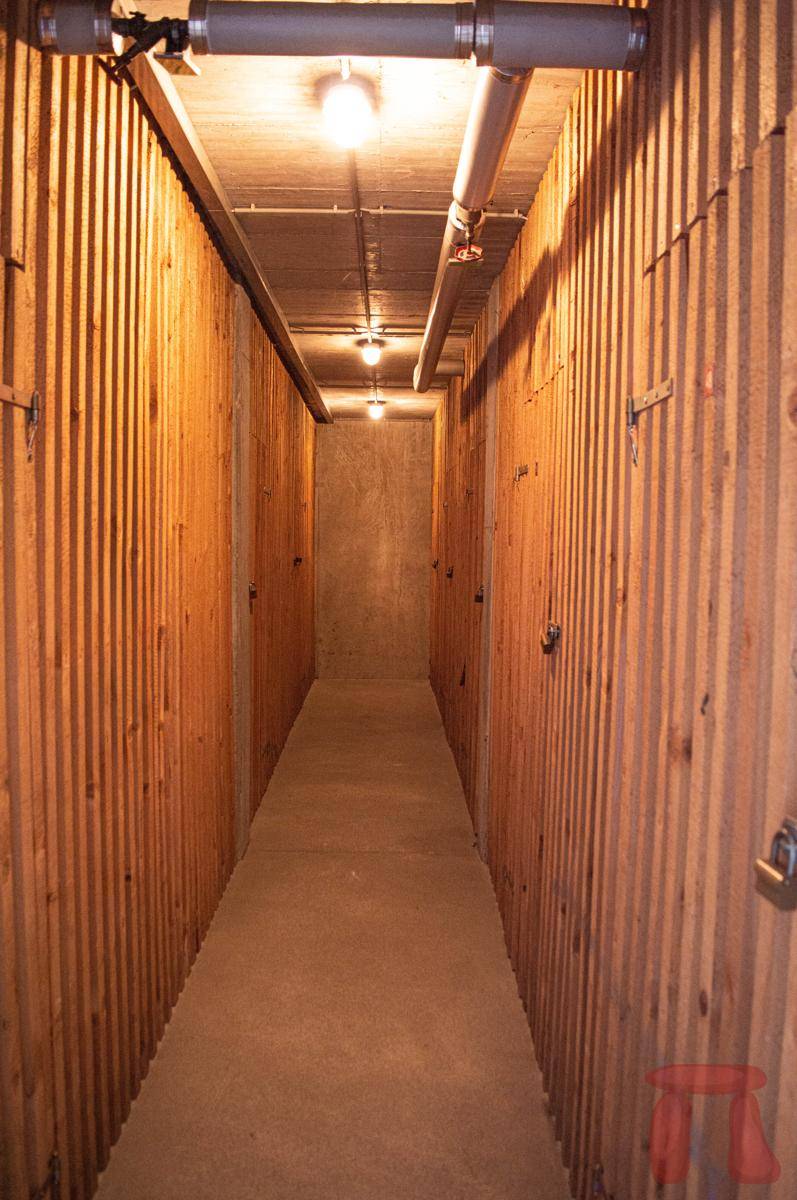 Langer Kellerflur mit Holzverschlägen als individuelle Abstellräume für Bewohner des Hauses.