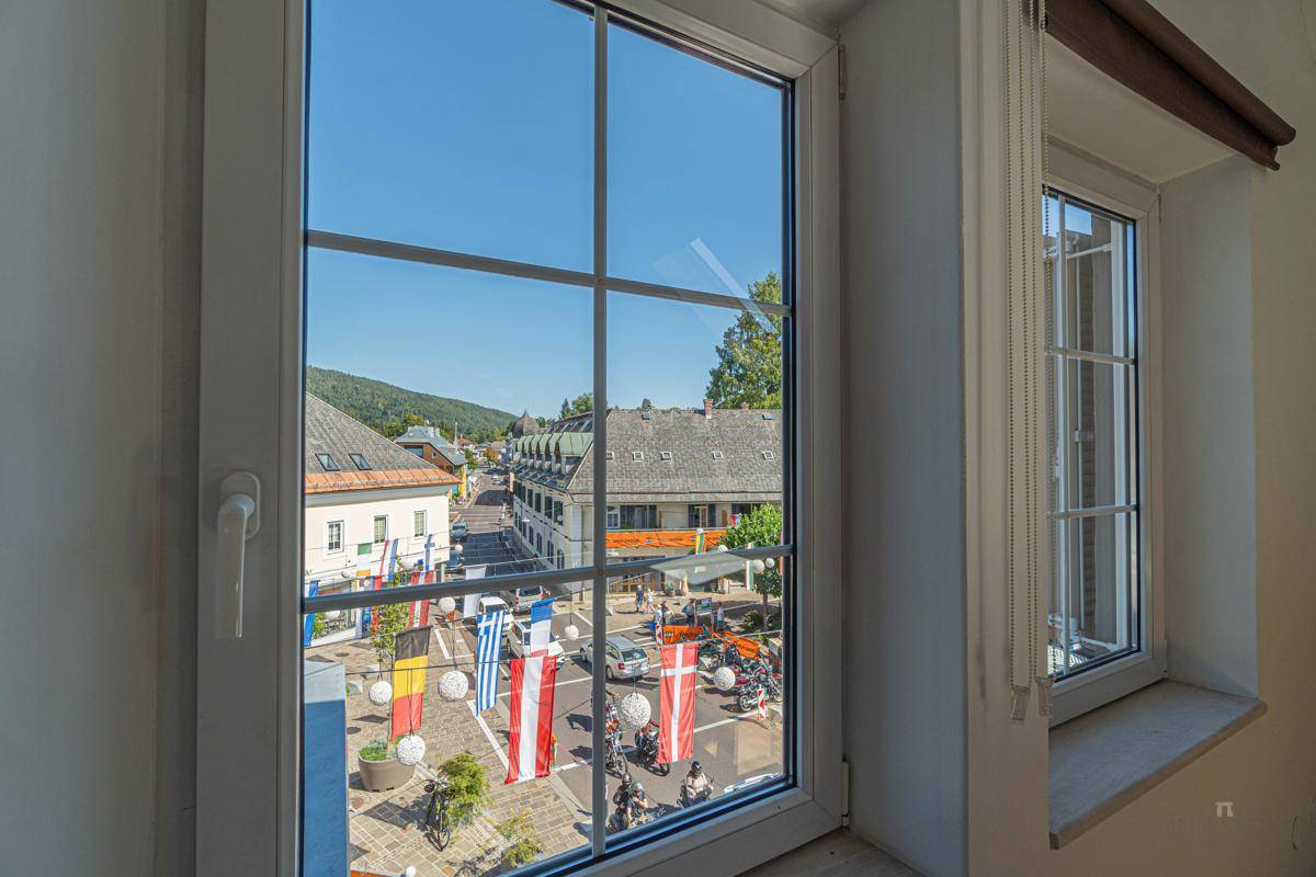 Blick aus dem Fenster auf eine belebte Straße mit Gebäuden und festlicher Dekoration.