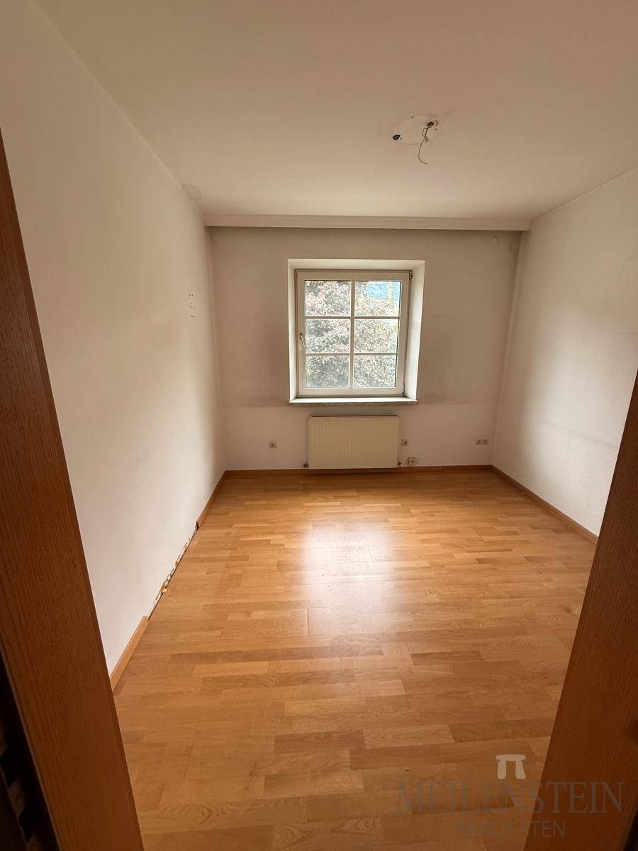 Helles Schlafzimmer mit Laminatboden und Fenster, das auf eine neue Einrichtung wartet.