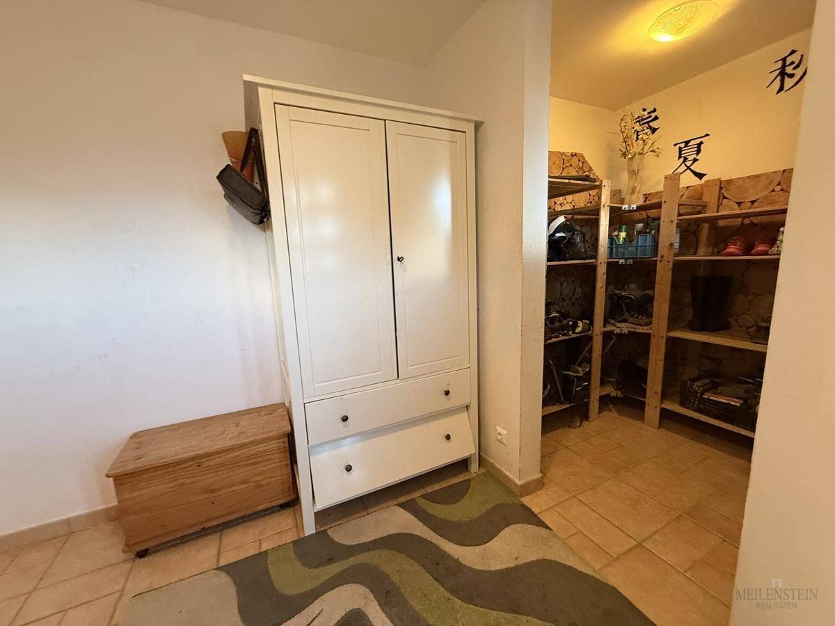 Praktischer Abstellraum mit Regalen für Schuhe und Kleidung, gut organisiert und funktional.