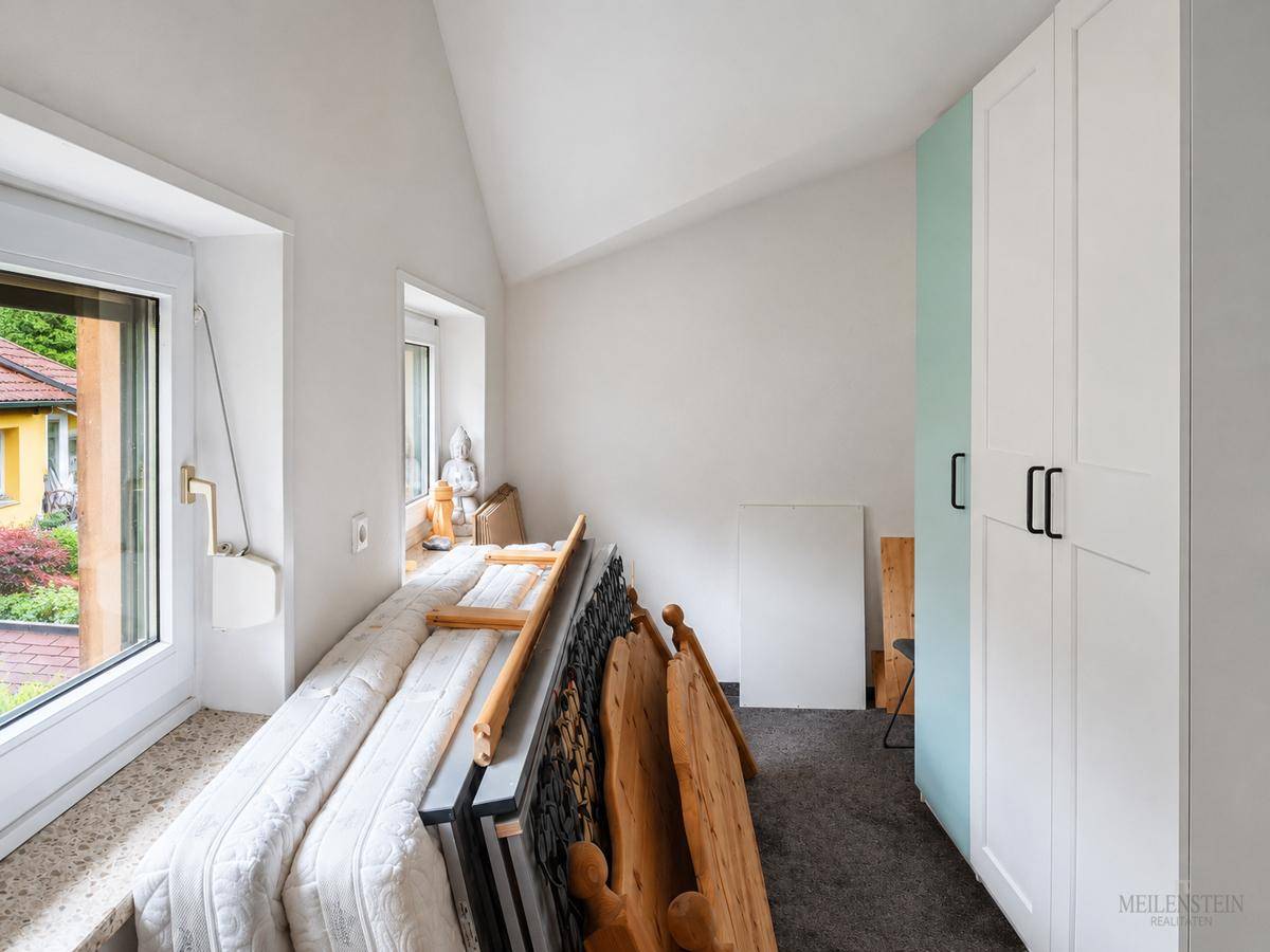 Dachgeschosszimmer mit Schrägen, genutzt als Abstellraum, mit Kleiderschrank und Matratzen.