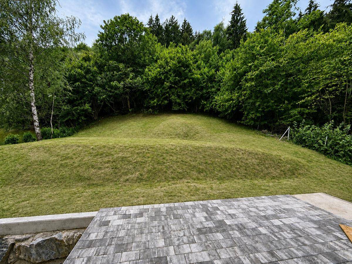 Großzügige gepflasterte Terrasse mit weitem Blick auf eine grüne Hügellandschaft und dichte Bäume.