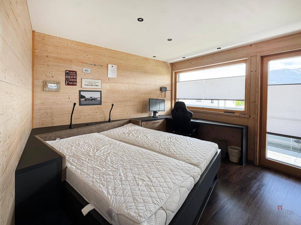 Schlafzimmer mit Holzwänden, integriertem Bett und Schreibtisch am Fenster mit Ausblick.