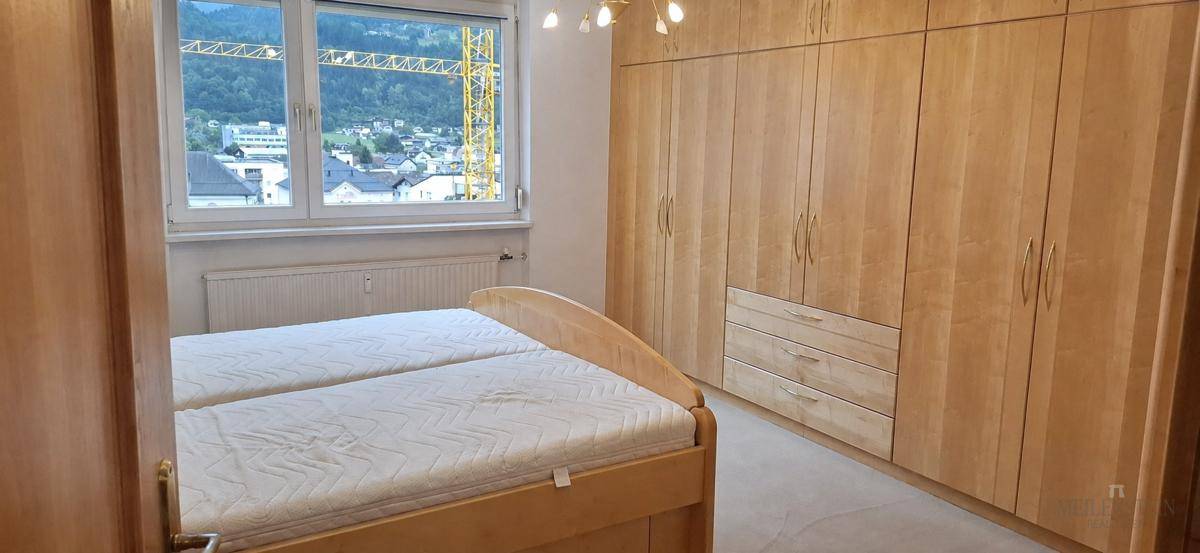 Schlafzimmer mit großem Einbauschrank aus Holz und Fenster mit Aussicht auf die Berglandschaft.