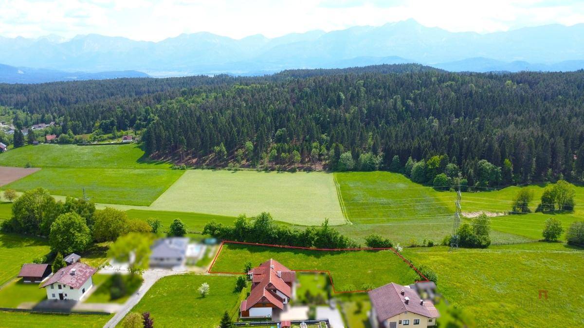 Panoramablick aus der Luft auf eine ländliche Gegend mit Bergen im Hintergrund und grünen Feldern.