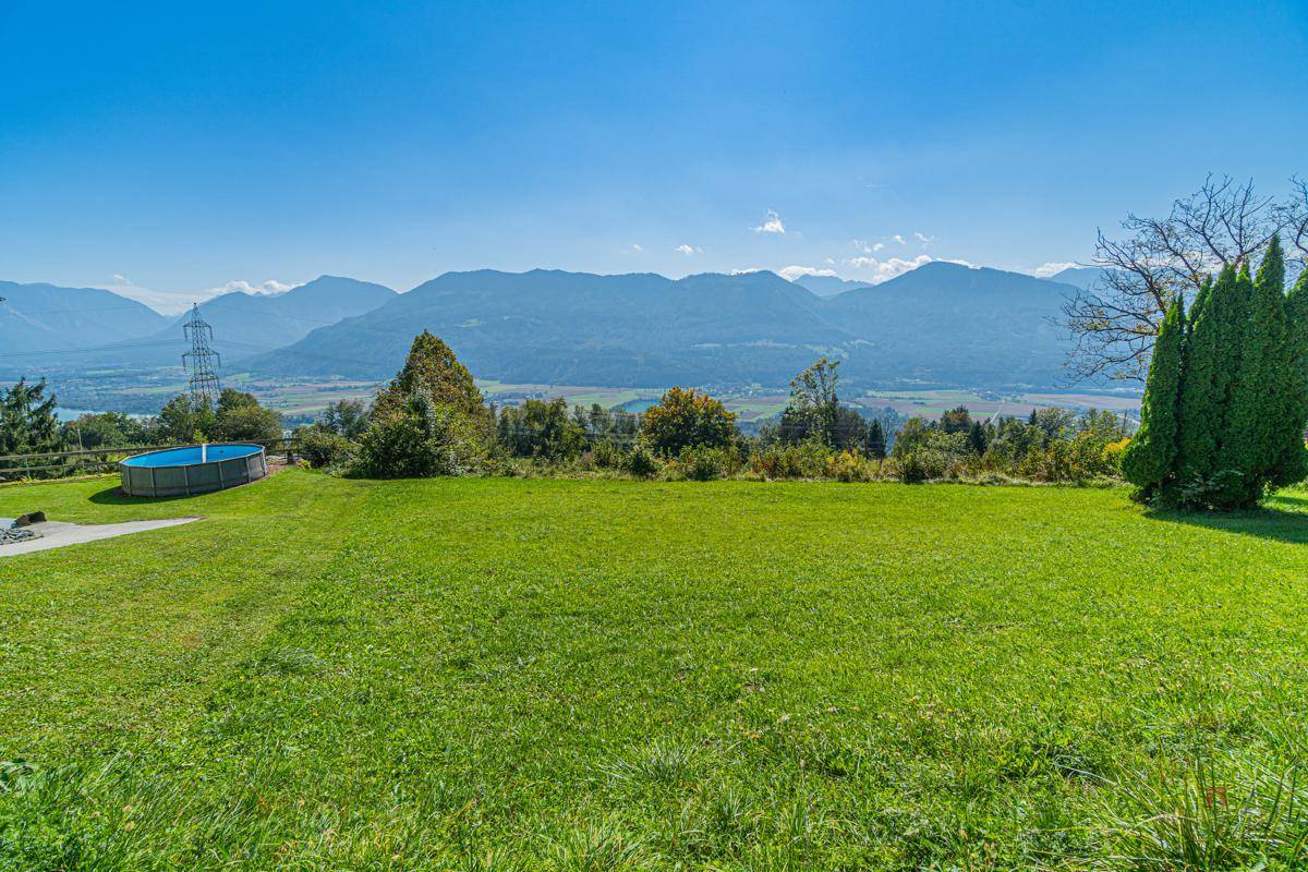 Weitläufige Rasenfläche mit einem Aufstellpool und beeindruckendem Blick auf die Bergkette.