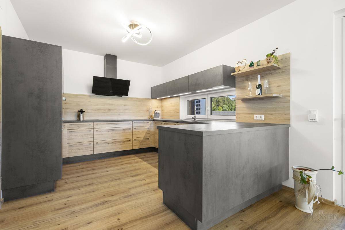 Moderne Einbauküche mit grauen und holzfarbenen Fronten, Kochinsel und Dunstabzugshaube.