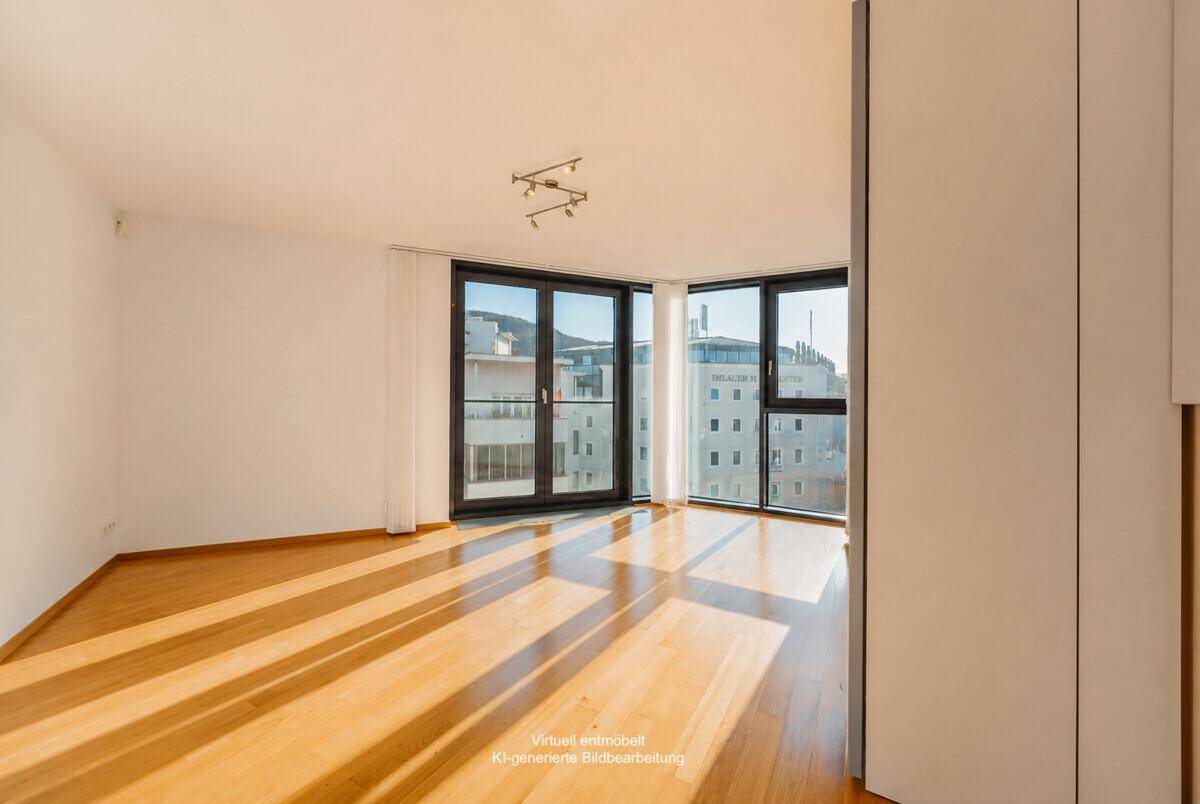 Helles, unmöbliertes Schlafzimmer mit Holzboden und großen Fenstern mit Stadtblick.