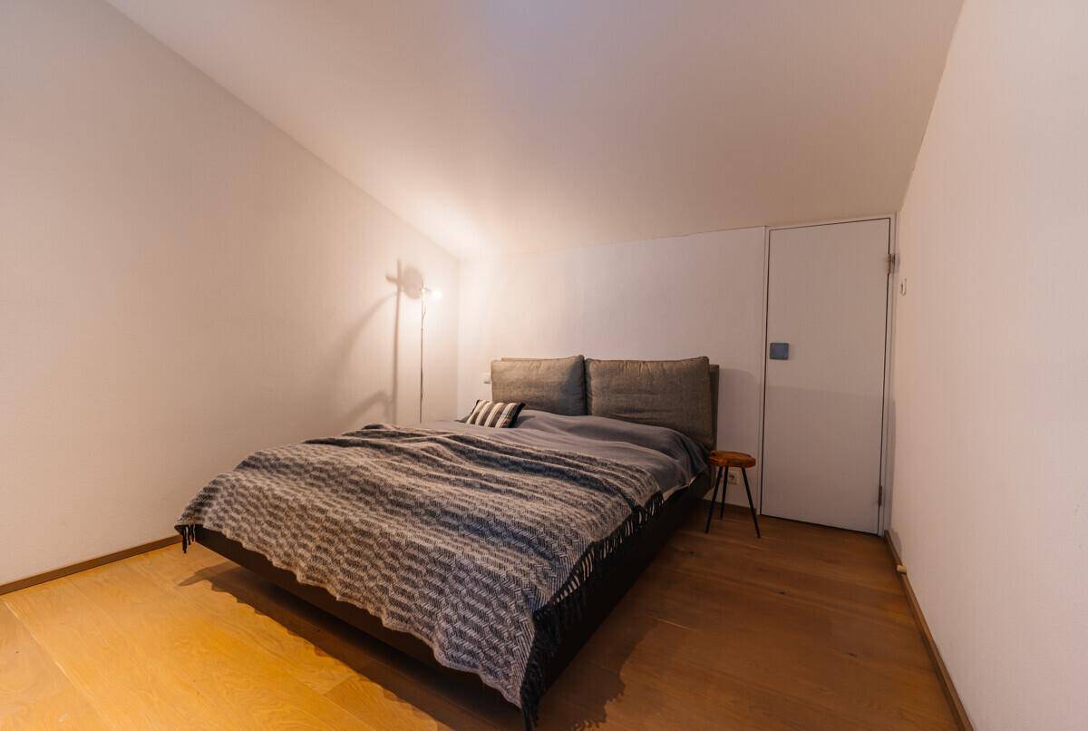 Schlafzimmer mit Holzboden, Doppelbett und minimalistischer Einrichtung in hellen Tönen, sehr ruhig.