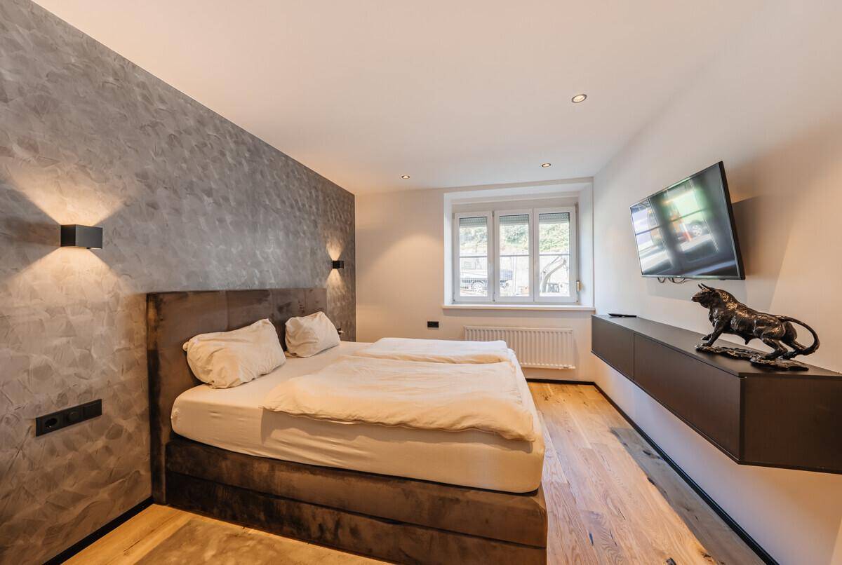 Gemütliches Schlafzimmer mit Doppelbett, Holzboden und einer strukturierten Akzentwand.