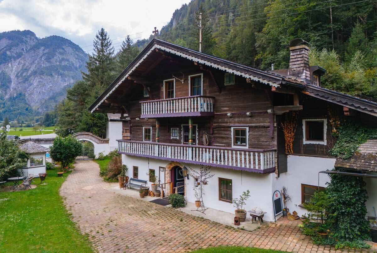Charmantes alpenländisches Haus mit Holzbalkonen und traditioneller Architektur vor Bergkulisse.