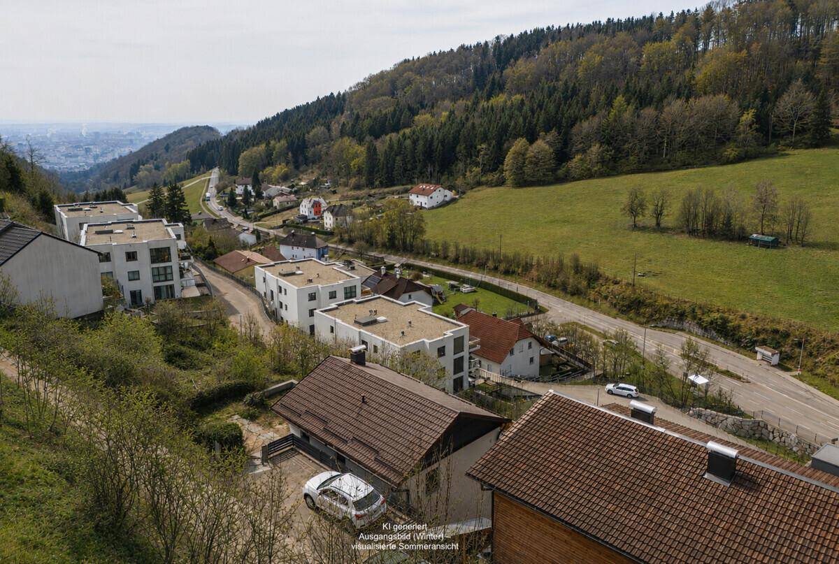 Luftaufnahme einer Wohnsiedlung in einer grünen Hügellandschaft mit Blick auf die Stadt in der Ferne.