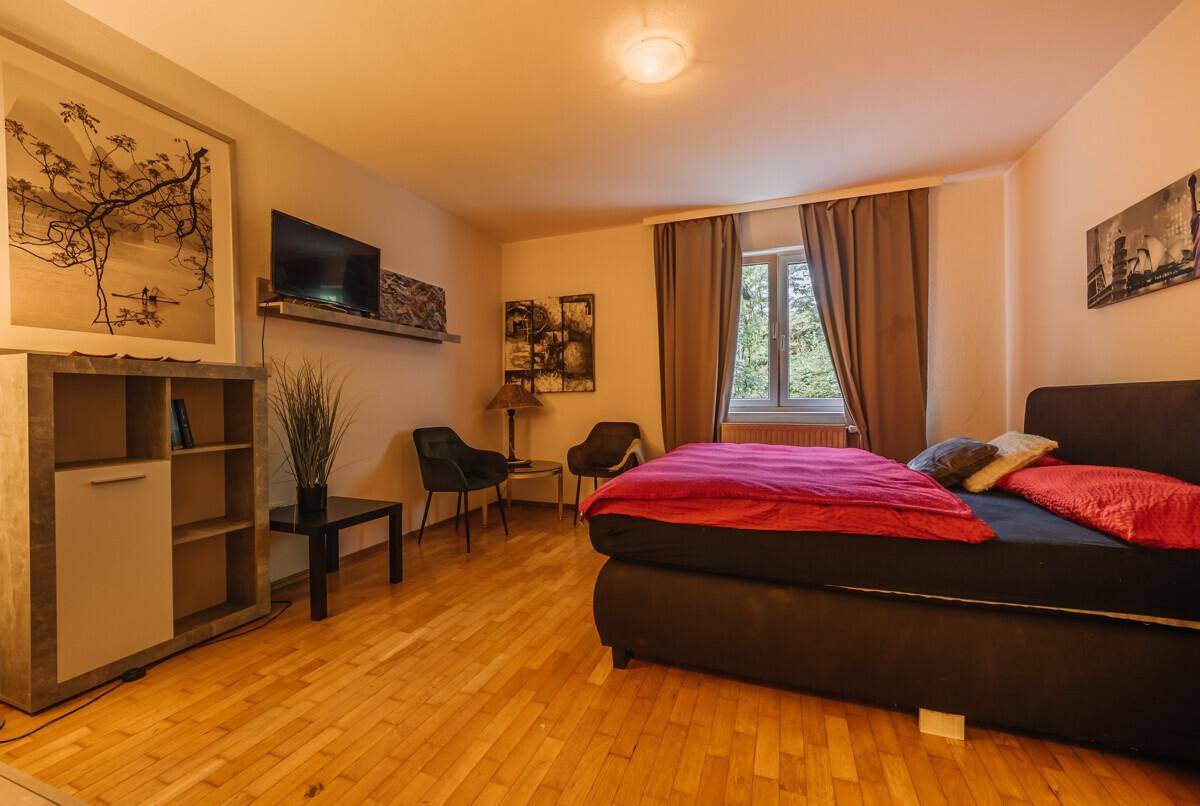 Gemütliches Schlafzimmer mit Holzboden, Doppelbett und moderner Dekoration, hell und einladend.
