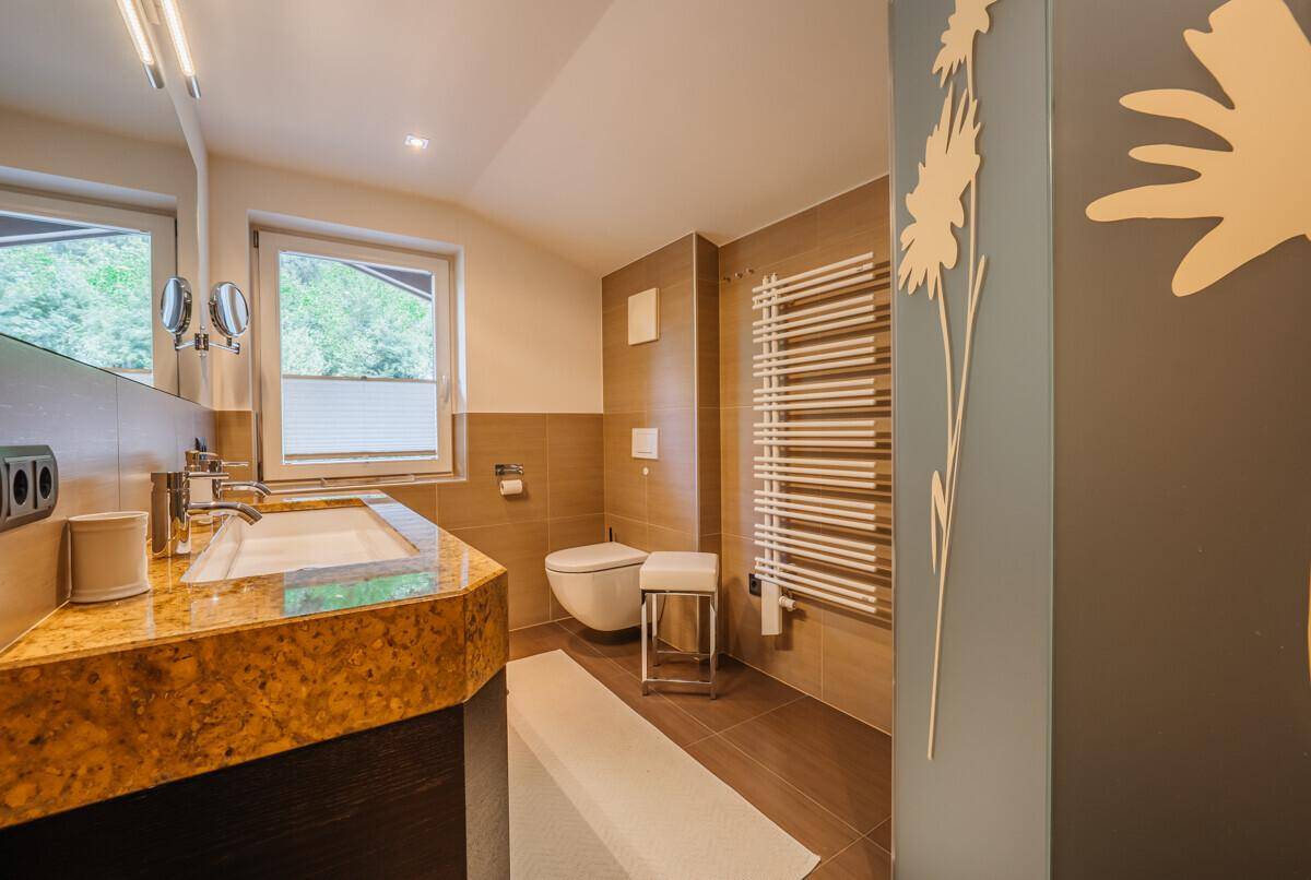 Modernes Badezimmer mit Doppelwaschbecken, beheiztem Handtuchhalter und Fenster.