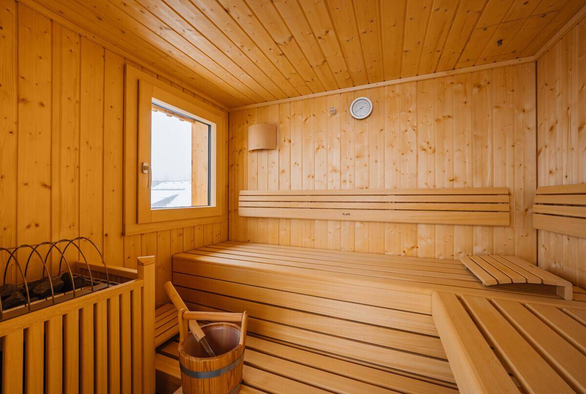 Traditionelle Holzsauna mit bequemen Bänken und Saunaofen für entspannende Momente.