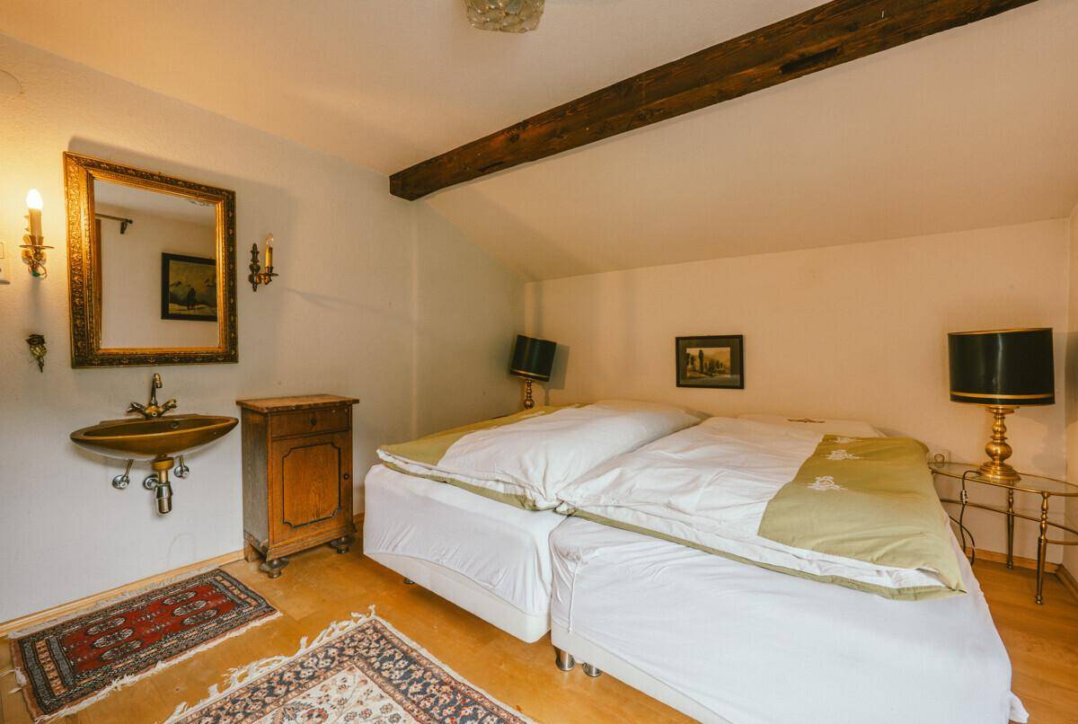 Gemütliches Schlafzimmer mit Holzbalken, Einzelwaschbecken und traditioneller Einrichtung.