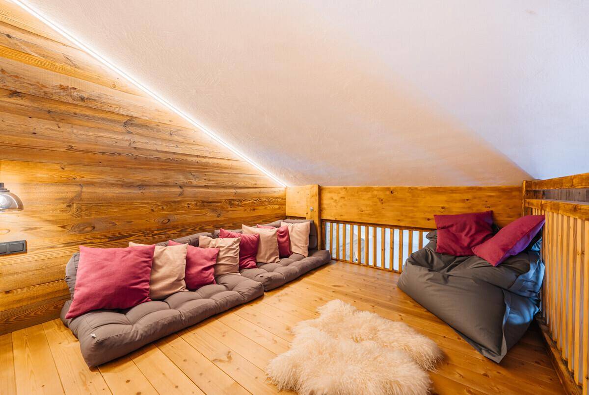 Gemütlicher Loungebereich unter einer Dachschräge mit Holzwänden und bequemen Bodenkissen.